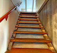Schodiště s dřevěným zábradlím a podlahou s dřevěným dekorem vede do patra budovy.
