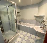 Koupelna v 3-pokojovém bytě se sprchovým koutem, vanou a světlou dlažbou.