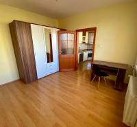 Ložnice v třípokojovém bytě s podlahou s dřevěným dekorem, šatní skříní a pracovním stolem.