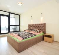 Ložnice v 3-pokojovém bytě s pohodlnou postelí a podlahou s dřevěným dekorem.