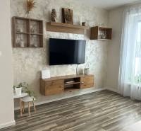Obývací pokoj v 3-pokojovém bytě s podlahou s dřevěným dekorem, zavěšenou TV a dekoracemi.