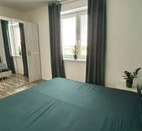 Ložnice v 3-pokojovém bytě se zrcadlovou skříní, závěsy a podlahou s dřevěným dekorem.