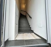 Vstupní prostor s tmavou dlažbou a schody v 3-pokojovém bytě.