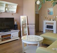 Obývací pokoj s televizí, krbem a podlahou s dřevěným dekorem v 2-pokojovém bytě.