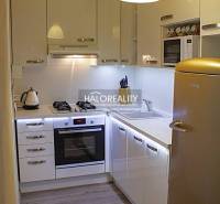 Kuchyně v 2-pokojovém bytě s bílými skříňkami a podlahou s dřevěným dekorem.