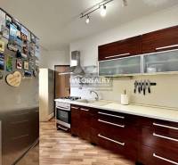 Kuchyně ve 3-pokojovém bytě s podlahou s dřevěným dekorem a spotřebiči.