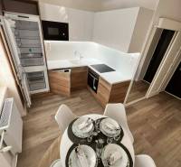 Kuchyně v 2pokojovém bytě s podlahou s dřevěným dekorem a jídelním stolem.