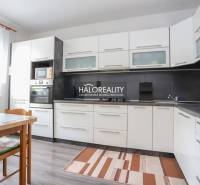 Kuchyně ve 3-pokojovém bytě s bílými skříňkami a podlahou s dřevěným dekorem.