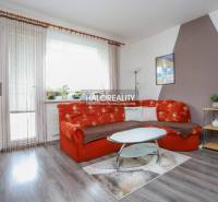 Obývací pokoj v 3-pokojovém bytě s oranžovou sedačkou a podlahou s dřevěným dekorem.