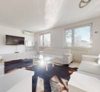 Obývací pokoj s bílým nábytkem, televizorem a proskleným stolem v bytě s 5 a více pokoji.