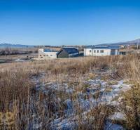 Pozemky k bydlení v Mlynici s panoramatickým výhledem a moderními stavbami v pozadí.