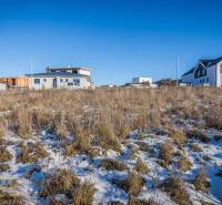 Pozemky - bydlení v Mlynici s výhledem na zasněžené hory a rodinné domy.