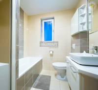 Koupelna s vanou a umyvadlem ve 2-pokojovém bytě, dominuje světlá dlažba.