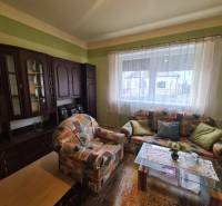 Obývací pokoj rodinného domu s barevnou pohovkou a tmavou obývací stěnou.