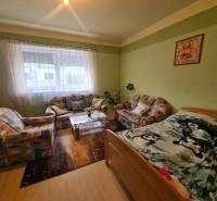 Obývací pokoj v rodinném domě s pohovkou, koberci a dekorativním obrazem na stěně.