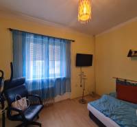 Pokoj v rodinném domě s cvičebním zařízením, křeslem a televizorem.