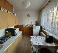 Kuchyně v 2-pokojovém bytě se spotřebiči a dlouhými záclonami přes okno.