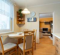 Jídelní kout ve 4-pokojovém bytě s podlahou s dřevěným dekorem, propojený s obývacím pokojem.