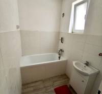 Koupelna v rodinném domě s vanou, umyvadlem a podlahou s dřevěným dekorem.