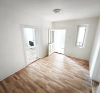 Pokoj v rodinném domě s podlahou s dřevěným dekorem a jednoduchým zařízením.