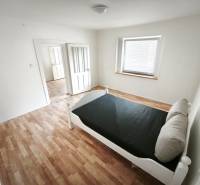 Světlý pokoj s postelí, podlaha s dřevěným dekorem, v rodinném domě.