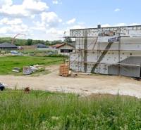 Stavební pozemek na bydlení v Modrovce s rozestavěnou budovou a okolím v pozadí.