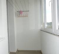 Zasklený balkon ve 3-pokojovém bytě s výhledem na městskou část.