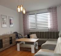 Světlý obývací pokoj s rohovou sedačkou, stolkem a komodou ve 3pokojovém bytě.