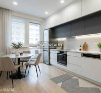 Jídelní kout s kulatým stolem a kuchyně s linkou ve 3-pokojovém bytě.