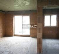 Rozestavěný interiér rodinného domu s velkými okny a nedokončenými stěnami.