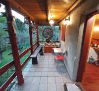 Venkovní terasa s dřevěným zábradlím a zahradou u chaty, nabízí klid.