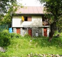 Útulná chata obklopená bujnou zelení a stromy v přírodním prostředí.