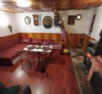 Rustikální chata, dřevěný strop, krb, pohodlná sedací souprava, tradiční interiér, příjemná atmosféra.