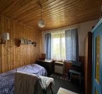 Pokoj v rodinném domě s dřevem obloženými stěnami, modrou skříní a postelí.