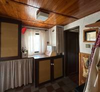 Interiér rodinného domu s dřevěným stropem a závěsy, útulný koutek s dekoračními prvky.