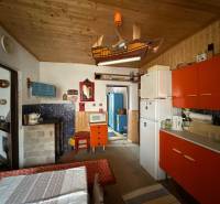 Rustikální kuchyně s barevnými skříňkami a dřevěným stropem v rodinném domě.