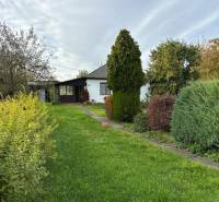 Rodinný dům v Kalši obklopený zahradou s různorodou vegetací.