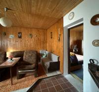 Interiér rodinného domu s dřevěným obkladem a pohodlným nábytkem s retro dekoracemi.