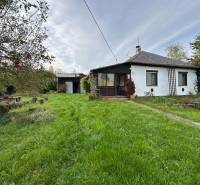 Rodinný dům v Kalši obklopený zahradou a ovocnými stromy, s upraveným trávníkem.