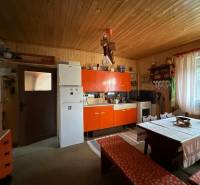 Kuchyně v rodinném domě se starožitným nábytkem, rustikální stěna, velké okno.