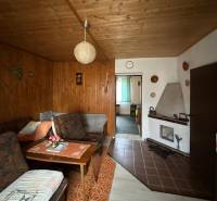 Obývací pokoj v rodinném domě s dřevěným dekorem stěn a stropu.