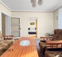 Rodinný dům s obývacím pokojem, květinovým nábytkem, konferenčním stolkem a obrazem na stěně.