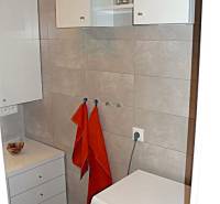 Koupelna s pračkou a úložným prostorem ve 4pokojovém bytě.