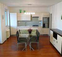 Kuchyně 4pokojového bytu s jídelním stolem a podlahou s dřevěným dekorem.