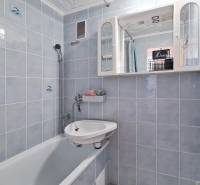 Koupelna s vanou a bílými obklady v 2-pokojovém bytě.