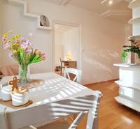 Jídelna v 2-pokojovém bytě s květinami na stole, podlaha s dřevěným dekorem.