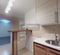 Kuchyně 2pokojového bytu s podlahou s dřevěným dekorem a barovým pultem.