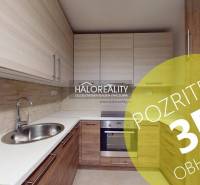 Kuchyně v 2-pokojovém bytě s podlahou s dřevěným dekorem a vestavěnými skříňkami.