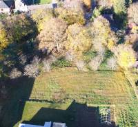 Komerční pozemky v Suchej nad Parnou s výhledem na zeleň a listnaté stromy.