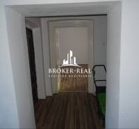 Chodba rodinného domu s podlahou s dřevěným dekorem a výhledem do další místnosti.